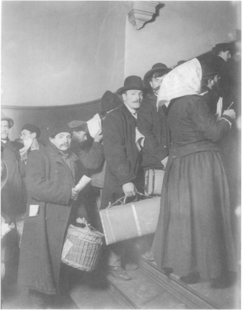 Immigrants carrying bundles and luggage climb a staircase at Ellis Island